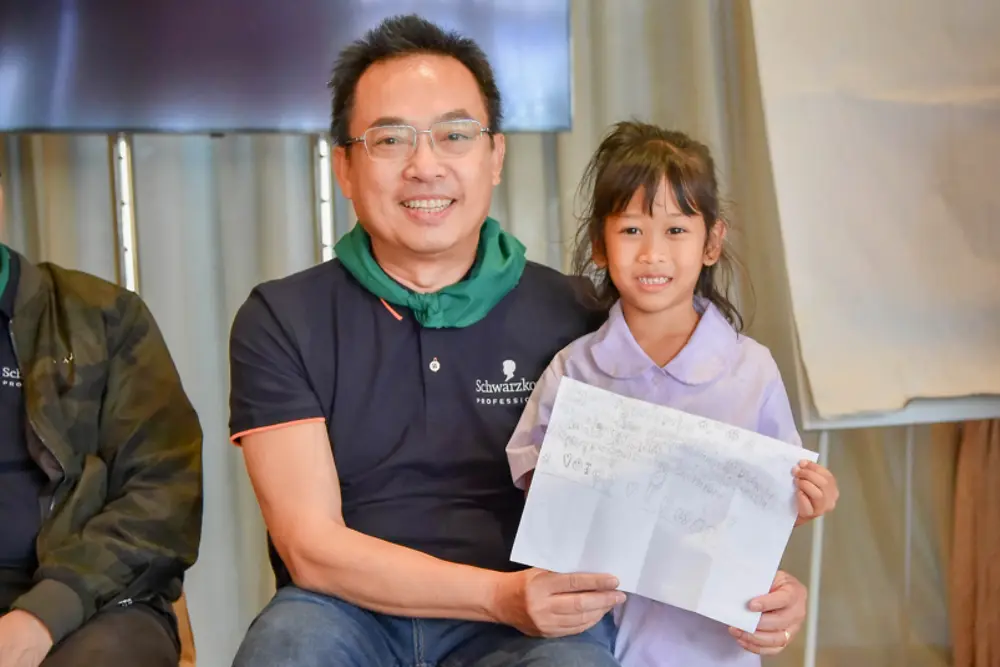 นายธีรศักดิ์ ไตรทิพย์ ผู้จัดการทั่วไปเฮงเค็ลบิวตี้แคร์ โปรเฟสชั่นแนล ถ่ายภาพร่วมกับนักเรียนอายุน้อยที่สุดที่เป็นผู้เขียนการ์ดขอบคุณทีมพนักงานเฮงเค็ล