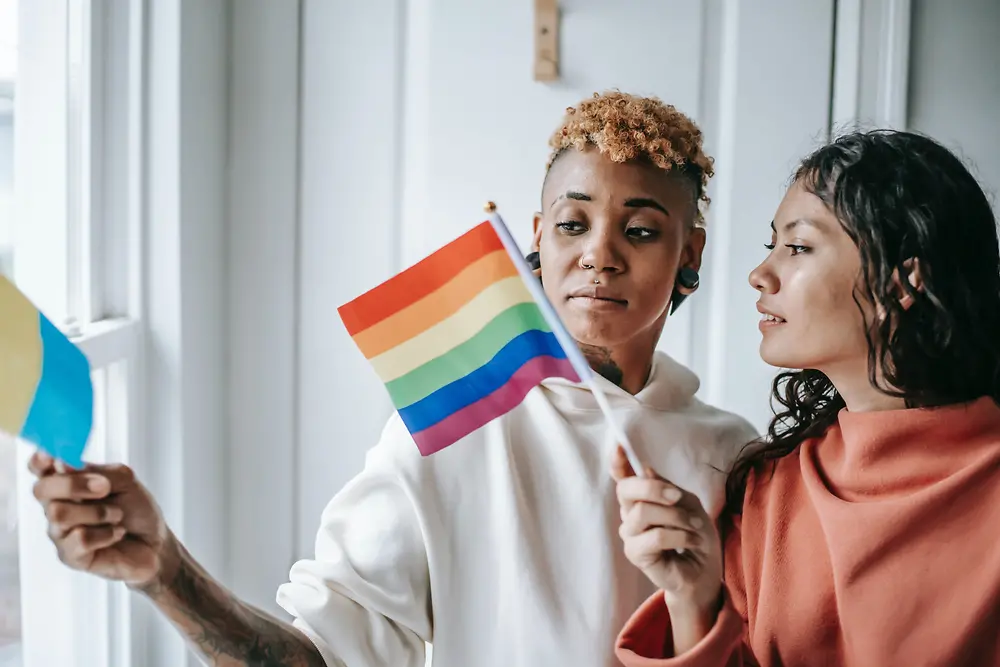 ผู้หญิงสองคนพูดคุยกันขณะถือธง LGBTQ+