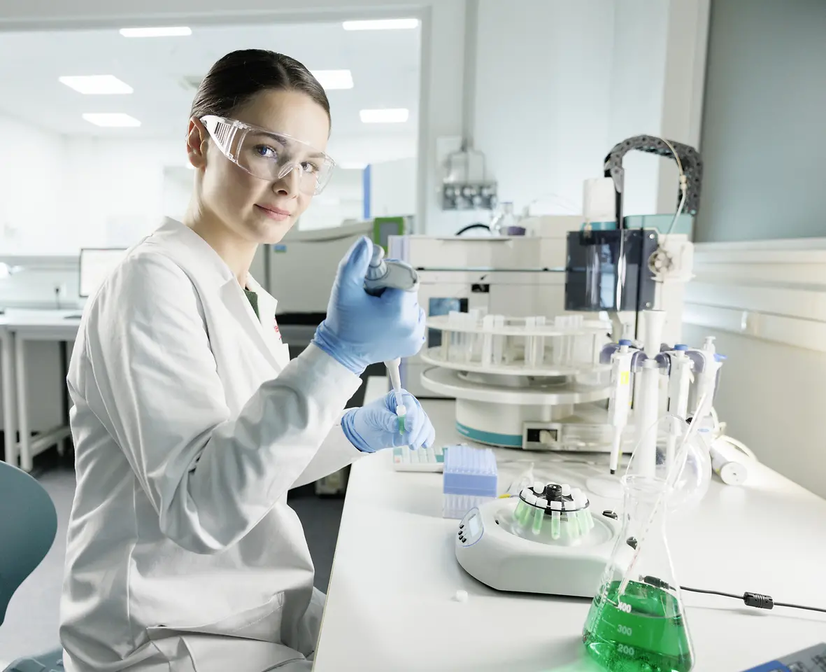นักวิทยาศาสตร์ผู้หญิงใส่เสื้อแลปและแว่นตาป้องกันความปลอดภัย กำลังทำการทดลองในห้องแลป 