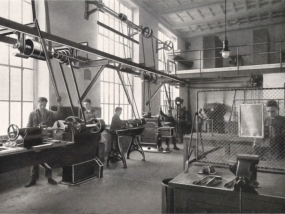 ผู้ฝึกงานกำลังทำงานกับเครื่องจักรในเวิร์กช็อปโลหะ